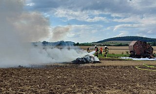Nach der Rundballenpresse (r.) musste auch noch gepresstes brennendes Stroh gelöscht werden. - FFW Warburg