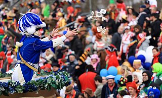 Ein Karnevalist wirft an Rosenmontag in Köln von einem Mottowagen Süßigkeiten ins Publikum. - Oliver Berg