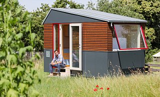 "Tiny-House" nennt man ein solch kleines Gebäude, vor dem Sascha Wagner sitzt. Die Grünen wollten wissen, ob es für diese minimalistische Wohnform auch in Verl Grundstücke geben könnte. - picture alliance/dpa/dpa-Zentralbild