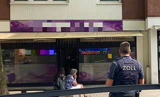 Ein Ermittler des Zolls vor dem Studio. Kollegen des Beamten überprüfen die Beschäftigten. - Jobst Lüdeking