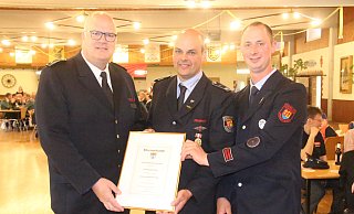 Der stellvertretende Kreisbrandmeister Jürgen Schmits (v. l.) überreicht Löschgruppenleiter Thorsten Dierkes Stellvertreter Dominik Hengst die Ehrenurkunde zum 100-jährigen Bestehen der Löschgruppe Bühne. - Burkhard Battran