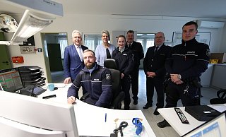 Weihnachtsbesuch bei der Polizei in Bünde: Landrat Jürgen Müller (stehend von links), Bürgermeisterin Susanne Rutenkröger, Theresa Klapper, Bernd Kröger, Uwe Köhler und Tim Wippermann. Am Schreibtisch der Wache sitzt Johannes Niederführ. Foto: Gerald Dunkel - Gerald Dunkel