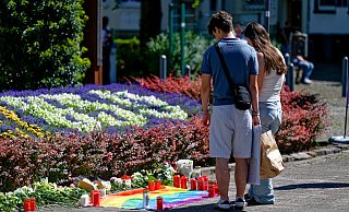24.08.2024, Nordrhein-Westfalen, Solingen: Nach der Messerattacke auf dem Solinger Stadtfest legen Menschen in der Nähe des Tatortes Blumen neben einer Regenbogenflagge nieder. Bei einer Attacke auf der 650-Jahr-Feier der Stadt Solingen hat es Todesopfer und Verletzte gegeben. Foto: Henning Kaiser/dpa +++ dpa-Bildfunk +++ - Henning Kaiser