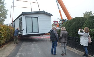 Ein Haus schwebt ein. Monika und Alfred Dierks haben sich bei E-Bay ihr neues Wohnhaus gekauft – ein Mobilheim, das mit dem Kran angeliefert werden muss. - Sibylle Kemna