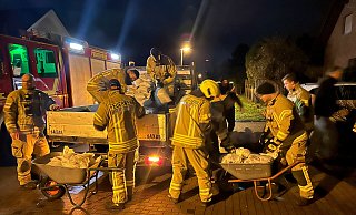 Einsatzkräfte der Feuerwehr Bad Lippspringe und Mitarbeiter des städtischen Bauhofs laden am Mittelgraben gefüllte Sandsäcke ab. - Ralph Meyer