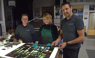 Echte Handwerkskunst: Ann Kathrin Striewe säubert gerade ein Glaselement, welches zu einem der Fenster aus Notre-Dame gehört. Die Glasmalerei GmbH von Stephan Lübbers (l.) und Stefan Lücking (r.) restauriert in Borchen derzeit zwei Fenster aus der weltweit bekannten französischen Kathedrale. - Mark Heinemann