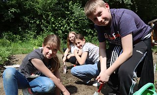 Jordan (v. l.) von der Schulgarten-AG unterstützt Leonie, Estella und Kiv aus der 5b beim Pflanzen. - Judith Gladow