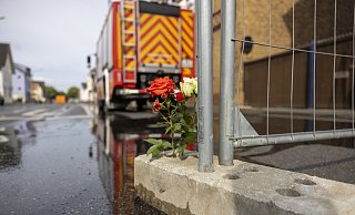 Blumen stehen an dem Absperrgitter in der Straße in Sankt Augustin, wo am Sonntag ein Motorradgeschäft brannte. Dabei starben zwei Feuerwehrleute. Die Anteilnahme bei der Feuerwehr im Kreis Höxter ist groß. - Thomas Banneyer