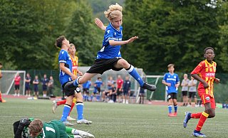 Im Spiel des U-14-Nachwuchscups überspringt Arminias Ole Makuc den Paderborner Torhüter fair. Im Hintergrund ärgert sich der Bielefelder Torschütze Erkan Ünal über die verpasste Chance beim 1:1 im OWL-Derby. - Peter Unger