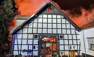Im Inneren ist es, wie durch die gläserne Eingangstür sichtbar, feuerrot. Vor dem Haus parken noch Bobbycars der Tagespflege. - Feuerwehr Bad Oeynhausen