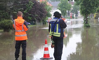 Feuerwehrleute sperren eine überflutete Straße in Bünde ab. - Florian Weyand