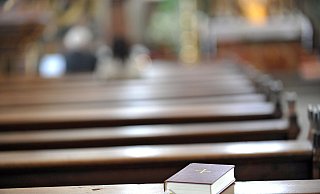 Ein Gesangbuch liegt verlassen in einer Kirchenbank. - Jens Schulze / epd
