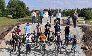 Probefahrt auf der fertigen Biker-Anlage: Heike Vahle vom Bauamt, HoT-Leiter Harry Lause, Unternehmer Leon Dierks, Bürgermeister Michael Berens, Jeff Schugk mit seinem Vater, Profi-Mountainbiker Kai Schugk (hinten v.l.) sowie eine Gruppe Hövelhofer Mountainbiker haben den Parcours gemeinsam getestet. - Gemeinde Hövelhof