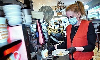 Ariane Haxha (40) zapft einen Cappuccino bei Knigge in der Obernstraße. Das Personal schützt sich weiterhin mit Maske, die Gäste dürfen auch ohne negativen Schnelltest Platz nehmen. - Barbara Franke