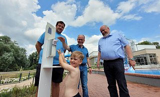 Der kleine Elias ist der erste Badegast, der sich am Sonnenmilchspender bedient. Bademeister Eike Henke (von links), Aqua-Fun-Geschäftsführer Oliver Weisheit und Bürgermeister Rüdiger Meier schauen dem Dreijährigen über die Schulter. - Florian Weyand
