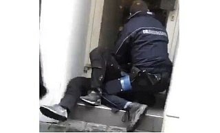 Dieser Screenshot zeigt, wie eine Ordnungskraft die Frau in einem Hauseingang liegend festhält. - Screenshot NW