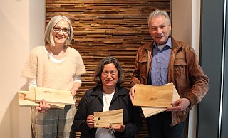 Nataly Kirwald (Natürlich Wohnen), Nadia Wadoud (März-Manufaktur) und Dietrich Honervogt (Freunde der Pader) zeigen die Schneide- und Schlüsselbrettchen, die aus dem Tornado-Holz gemacht sind. - Linda Schnepel