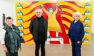 Fotografin Asimina Paradissa (l.) vor dem eigens für die Ausstellung von Serpil Yeter (r.) geschaffenen Wandbild „Rote Zukunft“. Von Mehmet Güler sind die Lithografien „Das Schicksal der Frauen“ zu sehen. Der Kittel an der Wand (hi. l.) gehört zu einer Installation von Nuray Demir. - Ralf Bittner