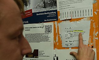 Ein Student sucht an der Universität Paderborn an einer Wand mit Aushängen nach einer passenden Wohnung. Unter den Anzeigen sind auch Wohnungsgesuche. - Marc Köppelmann