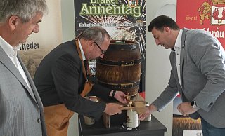 Pfarrer Andreas Kurte (M.) sticht bei seiner Annentags-Premiere in Amt und Würden das Bierfass an. Bürgermeister Hermann Temme (l.) und Markus Lopsien von der Schlossbrauerei Rheder unterstützen. - Svenja Ludwig