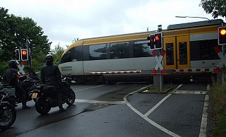 In Sekundenschnelle hat die Eurobahn den Bahnübergang an der Gestringer Straße passiert. Hier wartet gerade eine Clique holländischer Motorradfahrer, die den Mühlenkreis am Wochenende erkunden, darauf, dass die Schranken wieder hochgehen. - Karsten Schulz