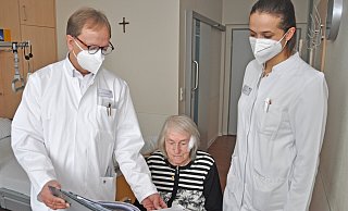 Chefarzt Norbert Bradtke und Apothekerin Franziska Herrmann besprechen mit der Patientin Irmgard Pollmann, welche Medikamente eingenommen werden müssen. - Brüderkrankenhaus St. Josef