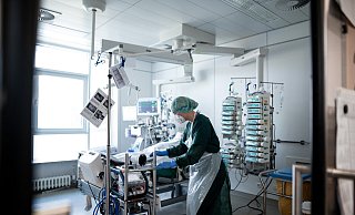 Eine Pflegekraft steht in einem Zimmer der Corona-Intensivstation und behandelt einen Patienten. - Fabian Strauch