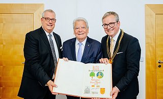 Gildemeister Johannes Beverungen (v. l.), Joachim Gauck und Bürgermeister Michael Dreier zeigen die Seite im Goldenen Buch mit dem Eintrag des früheren Bundespräsidenten. - Besim Mazhiqi