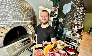 Benjamin „Benni“ Demir präsentiert eine Frühstücksplatte. Neben ihm ist der italienische Pizzaofen zu sehen. - Jens Reddeker