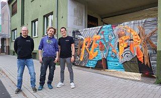 Andre Diekwisch (l.) und Lennart Engel (r.) vom Vorstand des FreiWerk Paderborn mit dem Künstler Lukas Michalksi. - Freiwerk