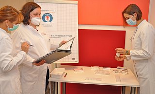 Margarete Niehues (PTA/v. l.), Oberapothekerin Stefanie Kuntze und Apothekerin Franziska Herrmann (v.l.) vor dem eigens präparierten mobilen Medikamentenstellplatz. Pflegende und Ärzte sollen in einer spielerischen Fortbildungspause herausfinden, wo Fehlerquellen lauern. - Brüderkrankenhaus St. Josef