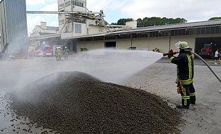 Brand im Pellet-Lager auf dem Bürener Bennenberg. Mit dem Sprühstrahl werden die glimmenden Pellets im Freien abgelöscht. - Ralph Meyer