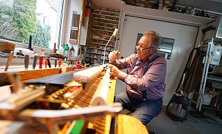 Jürgen Werner sitzt an einer Werkbank, auf der das Herzstück eines der Instrumente liegt. Auch heute ist der 76-Jährige noch täglich in der Werkstatt. - Gerald Dunkel