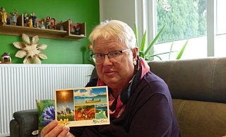 Im heimischen Wohnzimmer: Annette Aßbrock, mit einer Grußkarte, die nach 18 Jahren ihr Ziel fand. - Thorsten Mailänder