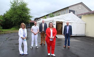Stadtsprecherin Sabine Hasenbein (v. l.), Apotheker Hauke Bitterberg, Bürgermeister Daniel Hartmann, Projektleiterin Nadine Nolte und Wirtschaftsförderer Volker Rodermund vor dem Nachsorgezelt hinter dem Impfgebäude der ehemaligen Förderschule in Lütmarsen. - Burkhard Battran