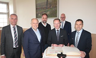 Bürens Bürgermeister Burkhard Schwuchow (r.) bittet Staatssekretär Daniel Sieveke, sich ins Goldene Buch der Stadt einzutragen anlässlich der Tagung des Deutschen Städte- und Gemeindebundes in der Wewelsburg. Auch der Beigeordnete Bernd Düsterdiek (v. l.), Landrat Christoph Rüther, Tobias Eschenbacher (Vorsitzender des DStGB-Ausschusses für Städtebau und Umwelt) und Christof Sommer (Hauptgeschäftsführer des Städte- und Gemeindebundes NRW) sind mit dabei. - Uwe Müller