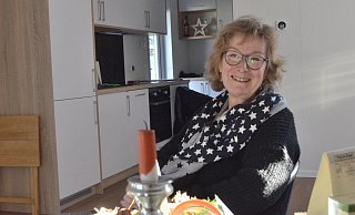 Monika Dierks (65) sitzt im noch kargen Wohnzimmer. Bisher steht dort nur ein Tisch mit zwei Stühlen. Die Küche im Hintergrund ist schon einsatzbereit. Der Kühlschrank kühlt, und frischer Kaffee wird aufgebrüht. - Sibylle Kemna