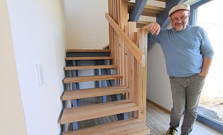 Holger Kasfeld steht im EIngangsbereich einer Wohnung, die sich über zwei Etagen erstreckt. Die Treppe ist aus Holz aus einem Kirchenwald in Bünde-Spradow gefertigt worden. - Björn Kenter