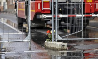 Blumen und Kerzen stehen an dem Absperrgitter in der Straße in Sankt Augustin, wo am Sonntag zwei Feuerwehrleute beim Brand in einem Motorradgeschäft starben. - Symbolfoto/ dpa