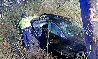 Nach dem Anprall an den Baum landete der schwer beschädigte BMW unterhalb der Dubelohstraße im Dickicht. Ein Polizeibeamter sichert Spuren. - Ralph Meyer