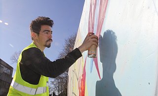 Reza Jaxon sprüht im Auftrag der Stadt Bad Oeynhausen die graue Betonfläche an der Rampe des Fahrradparkhauses. - Ulf Hanke