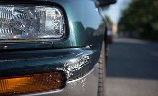 Am Stoßfänger eines geparkten Pkw sind Spuren eines Unfalls zu sehen. Nun reicht es nicht, einen Zettel am beschädigten Auto zu hinterlassen und wegzufahren. Das wäre Unfallflucht. - Arno Burgi/dpa