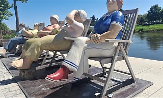 Alltagsmenschen in Liegestühlen an der Weserpromenade Höxter. Einer Frauenfigur fehlt jetzt ein Fuß mit Unterschenkel. - Simone Flörke
