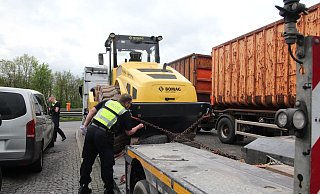 Ein Polizist überprüft die Ketten, mit denenein Erdverdichter auf dem Schwertransporter gesichert ist. - Jobst Lüdeking