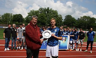 Übergabe der Meisterschale: Staffelleiter Kai Rieke (vorne .l.) gratuliert Herfords Kapitän Nico Bartling, dahinter haben sich die Mannschaft und die Verantwortlichen des SCH versammelt. - Thomas Vogelsang