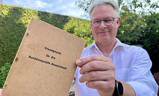 Das Grundgesetz aus dem Jahr 1950 bewahrt Jörg Schlüter daheim in Hövelhof auf. Für die Fotos hat er auf Handschuhe verzichtet, ansonsten wird das Büchlein sehr pfleglich behandelt. - Jens Reddeker