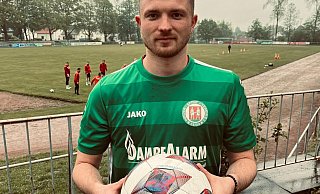 Sportliches Zuhause: Nico Bergmann steht mit dem Ball in der Hand vor dem Zugang zum Erich-Martens-Stadion, der Heimspielstätte des Bünder SV. - Florian Finke