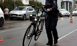 Eine Polizistin schiebt ein Fahrrad zum Streifenwagen. - Symbolfoto: Jens Reichenbach