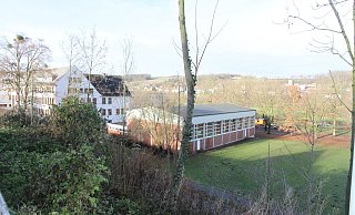 Im Hintergrund ist der sogenannte Neubau zu sehen, der aufgestockt werden soll. Rechts liegt die Turnhalle. - Johannes Büttner