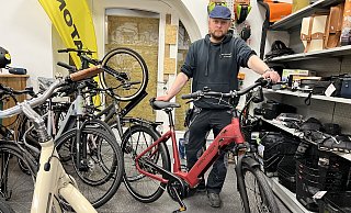 Einbruch in Werners Fahrrad Fach-Werk in Marienfeld: André Werner vor der zerstörten Seiteneingangstür und eines der Fahrräder, aus dem ein hochwertiger Rahmen-Akku gestohlen wurde. - Gabriele Grund